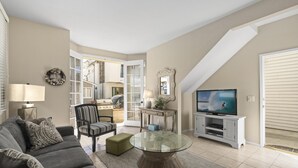 Un salon comprenant un canapé, une table basse en verre, un téléviseur et une cheminée.