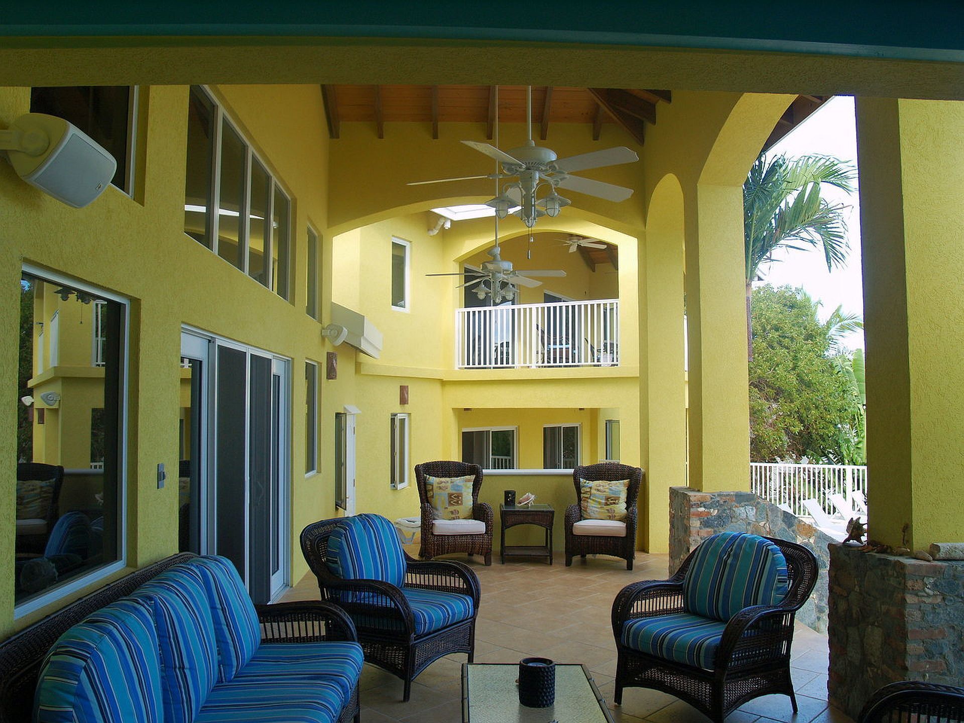 A covered outdoor area with wicker furniture, a ceiling fan, and a view of the outdoors.