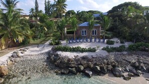 Situated on a sandy beach, this property offers stunning ocean views and comfortable outdoor seating.