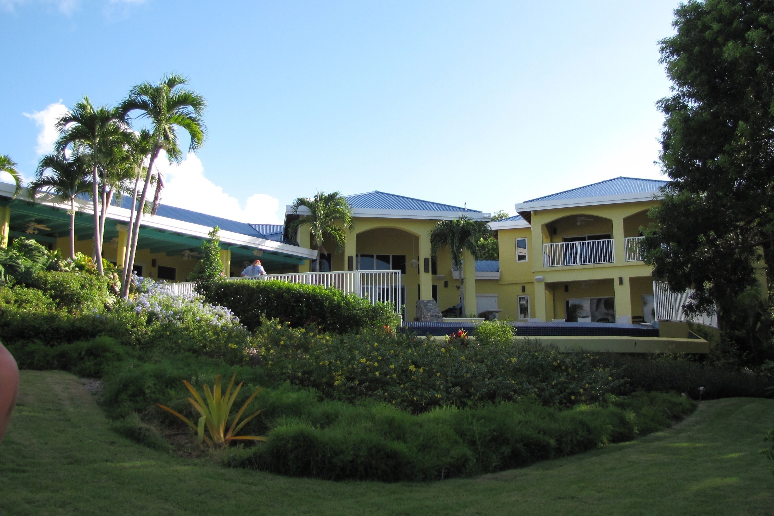A hotel with multiple yellow buildings, a covered walkway, and lush greenery.