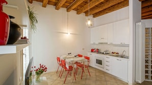 A compact kitchen with white cabinets, a red toaster, and a gas stove. - Appartamento al Duomo in the Historical center of the city (Vicenza)