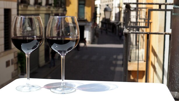 Two wine glasses on a table with a view of a narrow street and buildings in the background. - Appartamento al Duomo in the Historical center of the city (Vicenza)