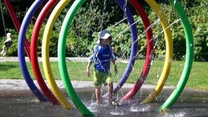A child playing through a water feature with multiple colorful rings.