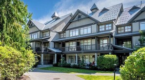 A multi-story building with a symmetrical facade, large windows, and a covered front porch.