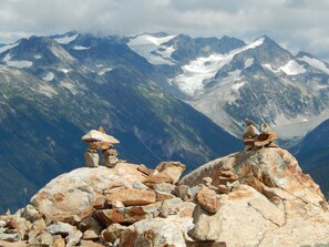 Eine Berglandschaft mit felsigem Gelände und schneebedeckten Gipfeln im Hintergrund.