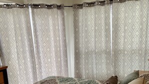 Une chambre à coucher avec un lit, des rideaux à motifs et un ventilateur de plafond.