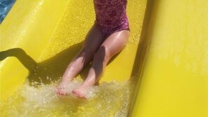 Un enfant glisse sur un toboggan aquatique jaune dans un parc aquatique.