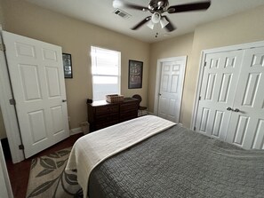 Cozy retreat with a large bed, dresser, chair, and window with blinds.
