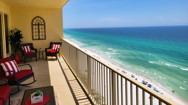 A balcony with a view of the beach and ocean.
