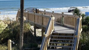 Une promenade en bois menant à une plage avec vue sur l’océan.