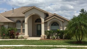 A two-story house with a beige exterior, a front porch, and a green door. - Elegant Paradise Villa...Disney Luxury Vacation Home (Clermont)