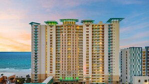 A high-rise hotel with multiple balconies, a prominent entrance, and a view of the ocean.
