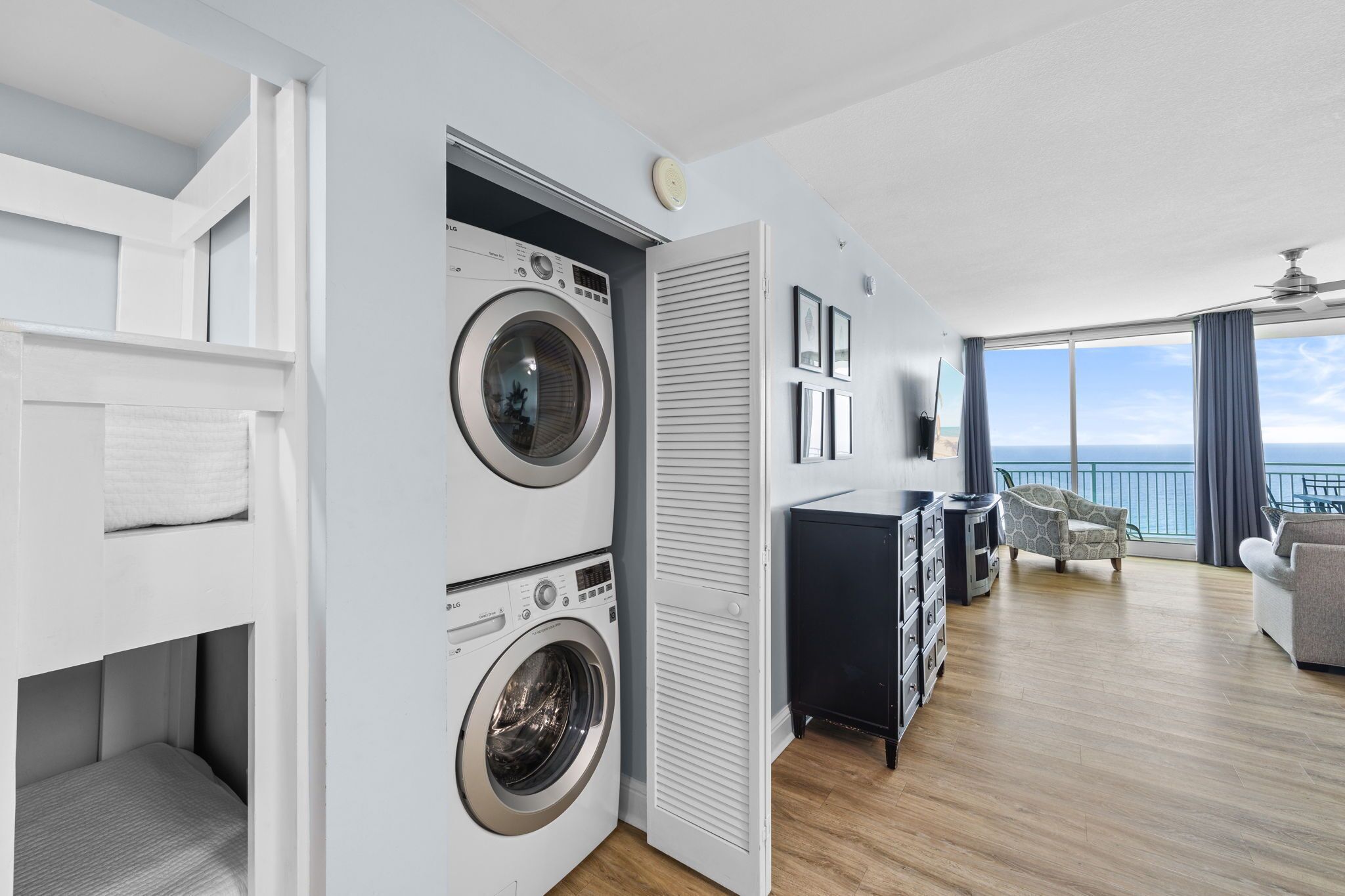 A modern apartment with a balcony, a washing machine, a TV, and a seating area.