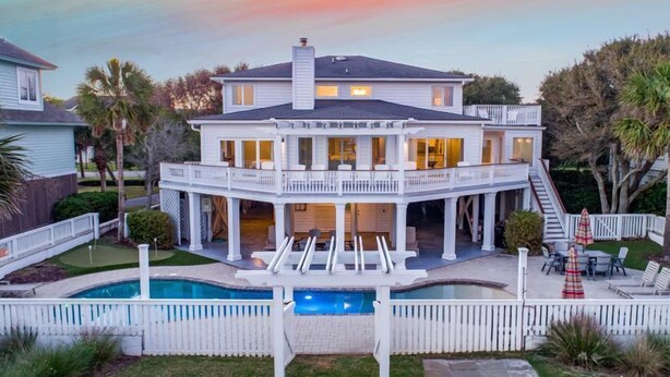 Uma casa de dois andares com piscina, varanda coberta e escada que dá acesso ao andar superior.