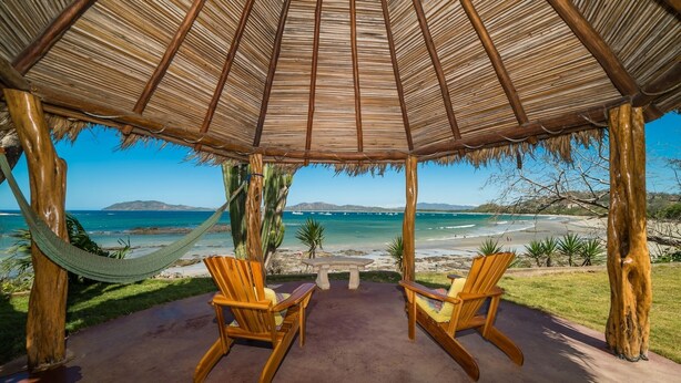A wooden gazebo with a thatched roof overlooking a beach. - Tamarindo's Hidden Gem, Tropical oasis 3 BR Beachfront Home, with private pool.
 (Tamarindo)