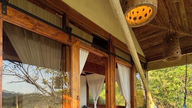 Amplia habitación con puertas correderas de vidrio, una hamaca y una cama con vista al exterior.