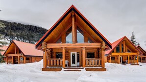 A log cabin with a prominent front porch and large windows, surrounded by snow. - Wonderful Rockies Cabin Getaway for Hike or Ski (Golden)