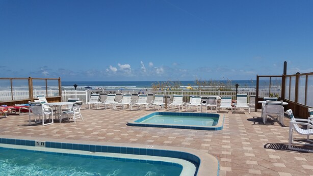 Un espace piscine aménagé sur le toit, avec des chaises longues et une vue sur la plage.