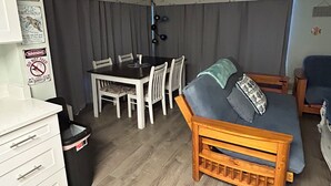 Un espace de vie compact comprenant un coin repas, un canapé, une petite table et un ventilateur de plafond.