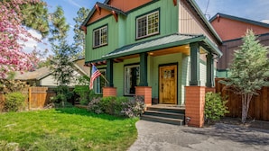A two-story house with a green exterior, a front porch, and a wooden door. - Fantastic location,  spacious and beautiful, perfect for groups, hot tub, dog ok (Bend)