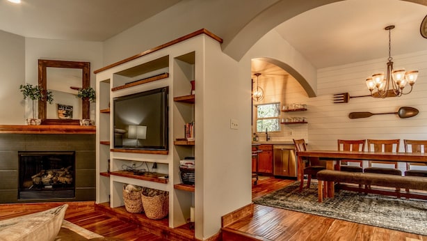 A cozy living room with a fireplace, wooden flooring, a TV, and a dining area with a chandelier. - Fantastic location,  spacious and beautiful, perfect for groups, hot tub, dog ok (Bend)