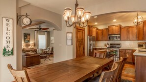 A spacious kitchen with wooden cabinets, a large dining table, and a chandelier. - Fantastic location,  spacious and beautiful, perfect for groups, hot tub, dog ok (Bend)