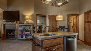 A kitchen with a built-in dishwasher, wooden cabinets, a fireplace, and a hanging light fixture. - Fantastic location,  spacious and beautiful, perfect for groups, hot tub, dog ok (Bend)