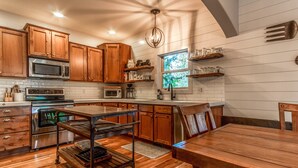 A kitchen with wooden cabinets, stainless steel appliances, and a wooden dining table. - Fantastic location,  spacious and beautiful, perfect for groups, hot tub, dog ok (Bend)