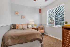 A bedroom with a large bed, a nightstand, a chair, a window with blinds, and wall art. - Beautiful 3,000sqft Home Perfect For Your Mountain Getaway! (Flagstaff)