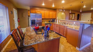 A kitchen with granite countertops, wooden cabinets, and stainless steel appliances. - A Desert Bloom House (Page)