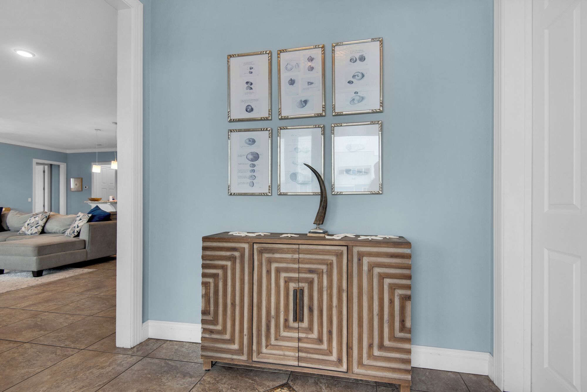 A living room with a light blue wall, a wooden cabinet with a geometric pattern, and framed pictures on the wall.