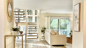 Amplia sala de estar con escaleras, un sofá y un gran ventanal con vistas a zonas verdes.