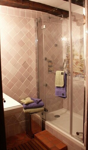 Une douche avec une porte en verre, un lavabo avec un porte-serviettes et une marche menant à la douche.