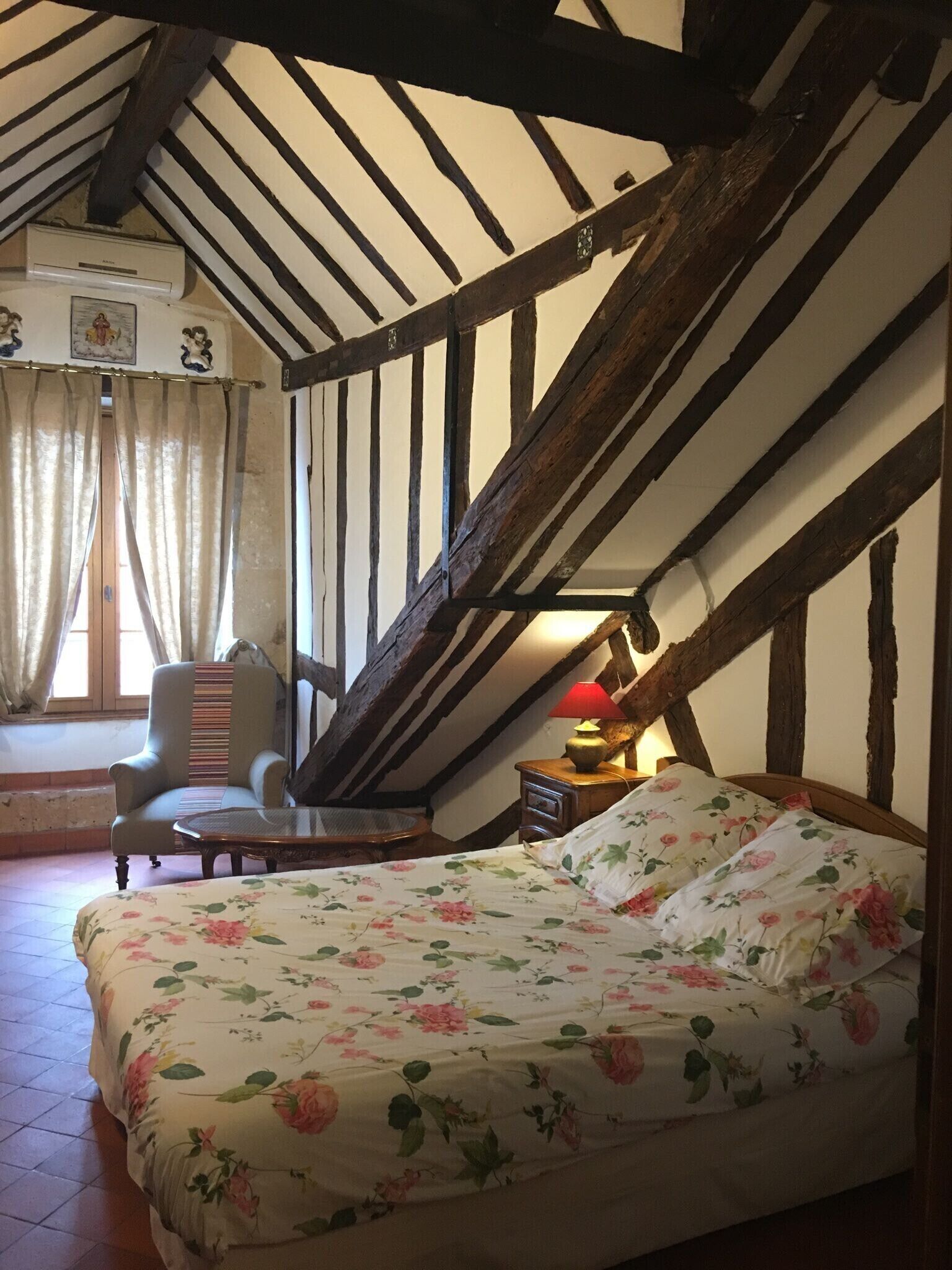 A bedroom with a bed, a chair, a table, and a lamp.