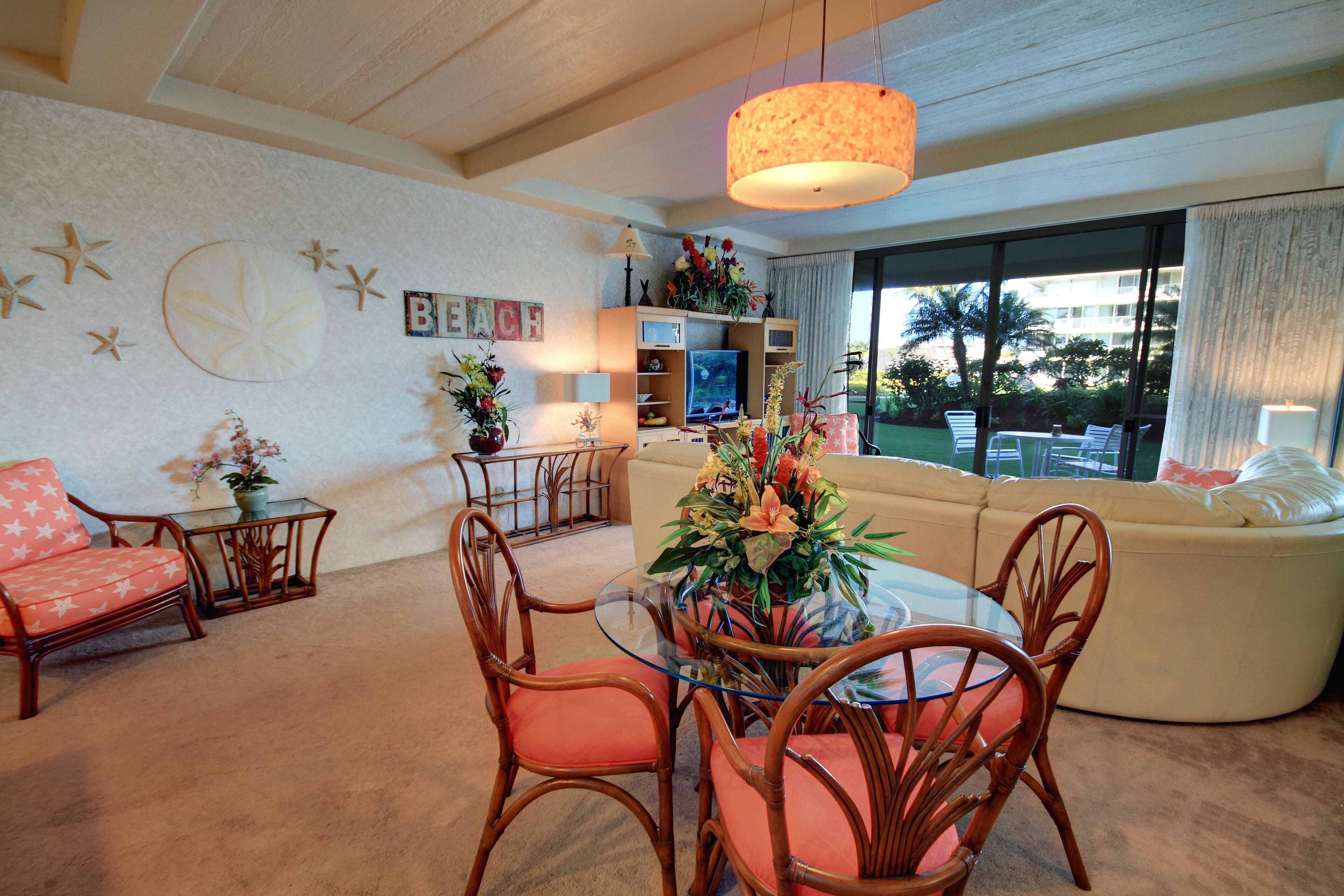 A living room with a glass coffee table, wicker chairs, a sofa, and a television.