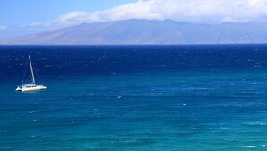 Un voilier sur une mer calme, avec une chaîne de montagnes en arrière-plan.