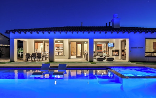 A modern house with a swimming pool, outdoor seating, and a fireplace.
