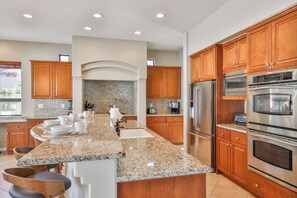 A spacious kitchen with granite countertops, stainless steel appliances, and wooden cabinetry.