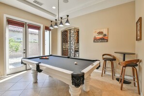 A pool table in a room with a door leading outside, a bar area with stools, and a California-themed wall decoration. - Serenity in the Desert - Slow Down and Reconnect at Gentle Breeze (Indio)