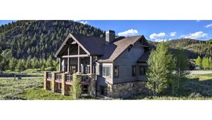Een houten chalet met twee verdiepingen, een stenen fundering, een balkon en een schoorsteen.