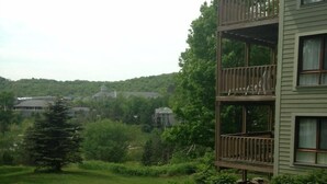 A multi-story building with a balcony, surrounded by a well-maintained lawn and trees.