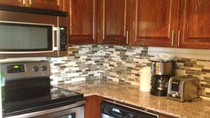 A kitchen with wooden cabinets, a microwave, an oven, a dishwasher, and a coffee maker.