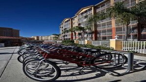 Varias bicicletas estacionadas frente a un edificio de varios pisos con balcones.