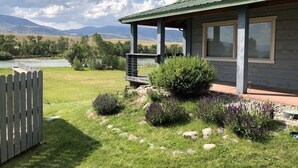 Et hus med en veranda, en lukket have og udsigt til en flod og bjerge.