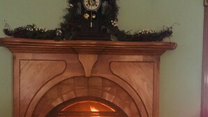 A fireplace with a clock above it, a vase to the right, and a wooden mantel. - Exquisite Accommodations Farmhouse with over 100 acres (Castleton)