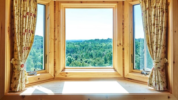 A room with a large window offering a view of a forest. - Exquisite Accommodations Farmhouse with over 100 acres (Castleton)