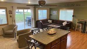 A cozy living room with a sofa, chairs, a coffee table, and a view of the outdoors. - Lake Winnebago Waterfront Cottage W/Hot Tub
[2 King; 1 Queen] (Fond du Lac)