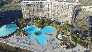 Un hotel de gran altura con una amplia piscina, varios balcones y un estacionamiento.
