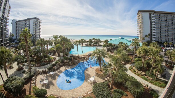 Un resort con piscina, palmeras y vistas al océano.