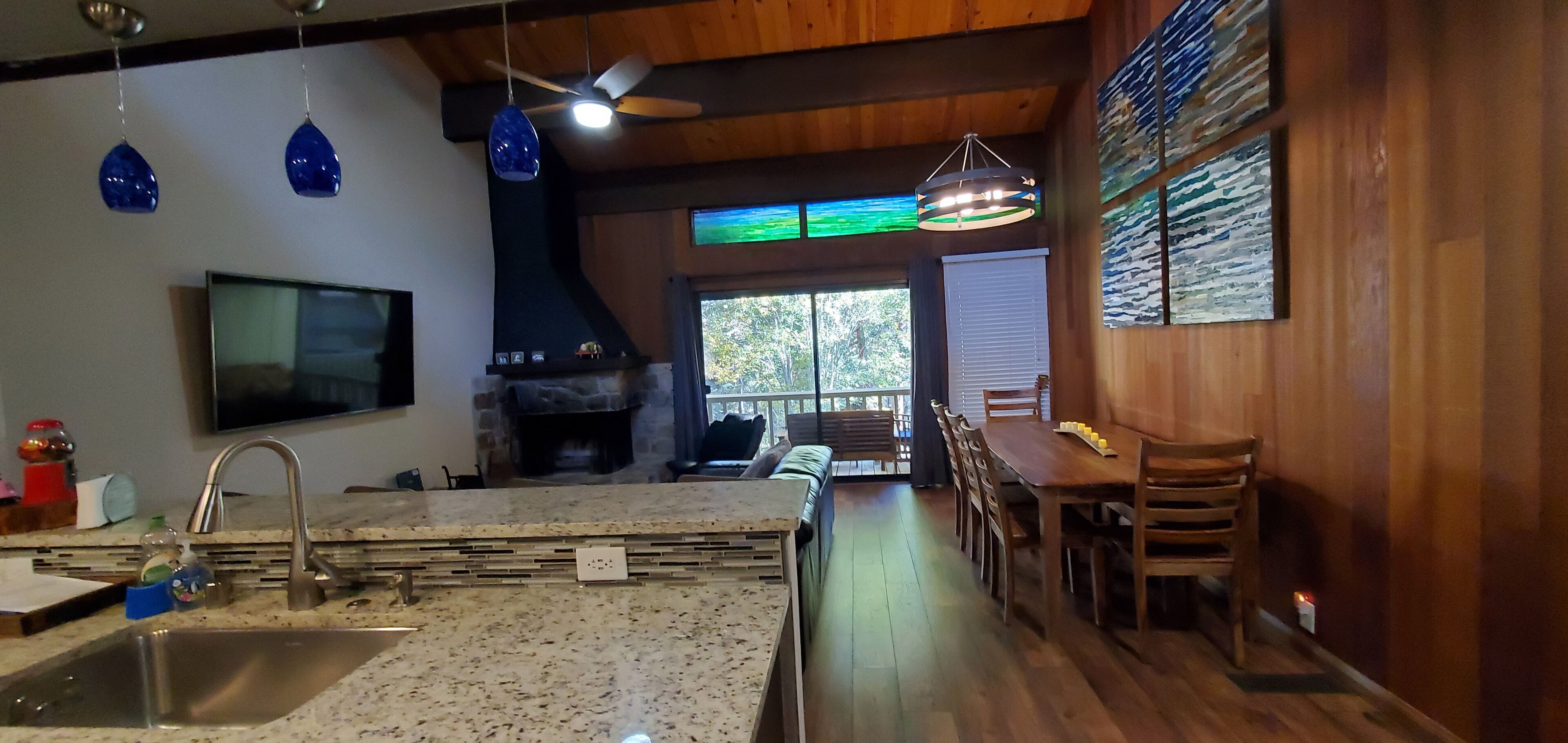 A modern kitchen with granite countertops, a built-in stove, and a dining area with wooden chairs and a table.